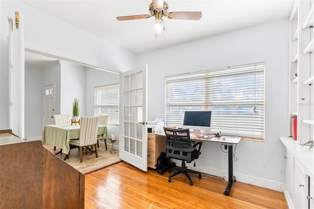 office space with light wood-type flooring, ceiling fan, and baseboards