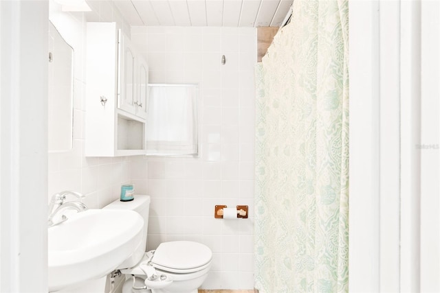 bathroom with toilet, tile walls, and a sink