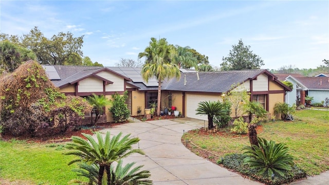 view of front of home with a garage, driveway, solar panels, a front yard, and stucco siding