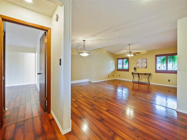 unfurnished room with lofted ceiling, dark wood finished floors, a ceiling fan, and baseboards