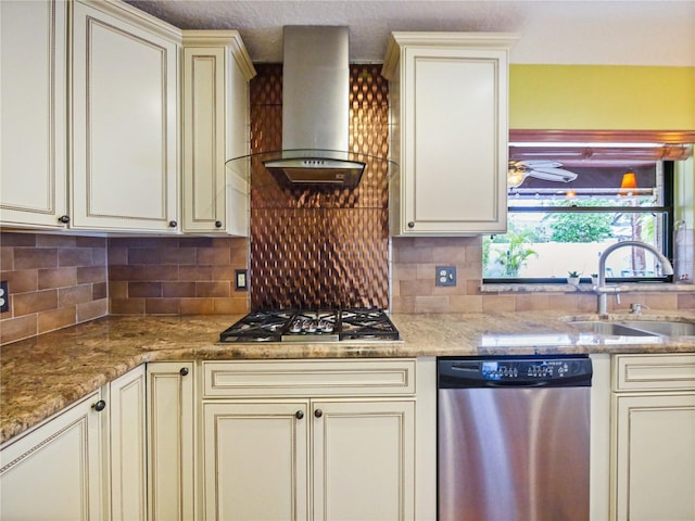 kitchen with stainless steel appliances, backsplash, cream cabinets, a sink, and wall chimney range hood