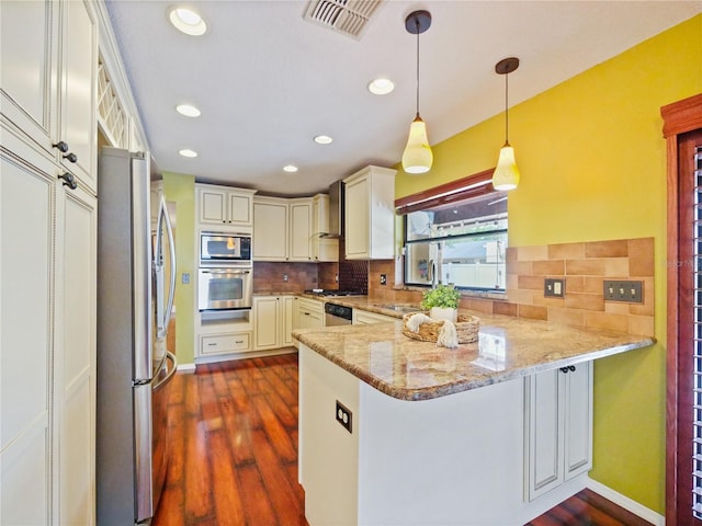 kitchen featuring a peninsula, visible vents, appliances with stainless steel finishes, light stone countertops, and decorative light fixtures