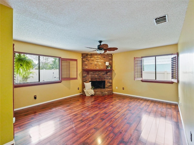 unfurnished living room with visible vents, baseboards, ceiling fan, dark wood-style flooring, and a brick fireplace