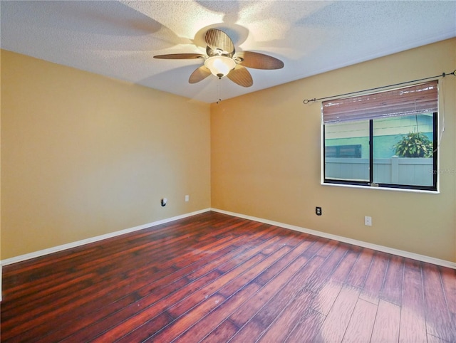 empty room with a textured ceiling, wood finished floors, and baseboards