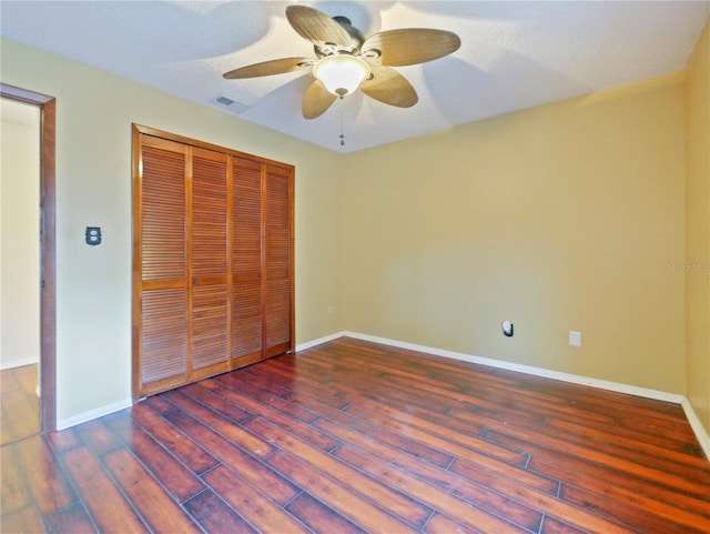 unfurnished bedroom with dark wood-type flooring, a closet, visible vents, and baseboards