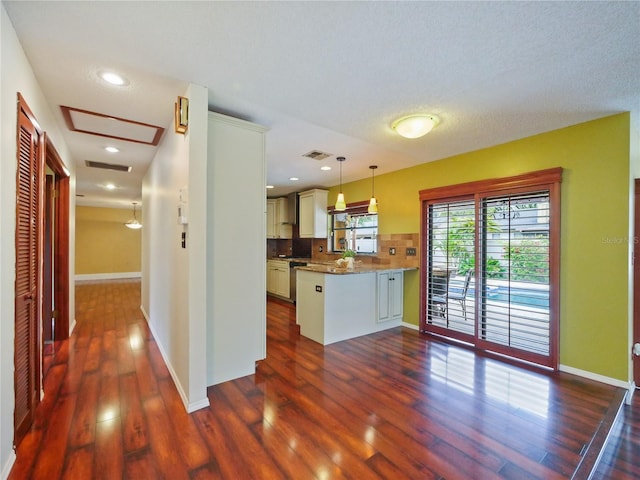 kitchen featuring dark wood-style floors, pendant lighting, tasteful backsplash, visible vents, and a peninsula