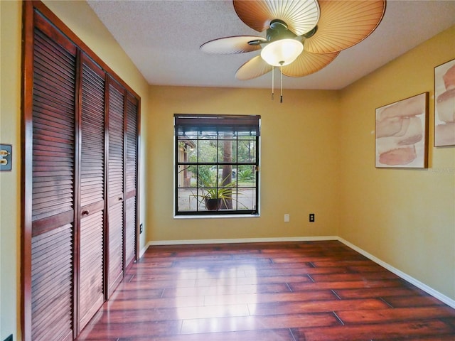 unfurnished bedroom featuring a closet, ceiling fan, baseboards, and wood finished floors