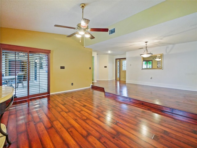 unfurnished living room featuring lofted ceiling, visible vents, baseboards, a ceiling fan, and dark wood finished floors