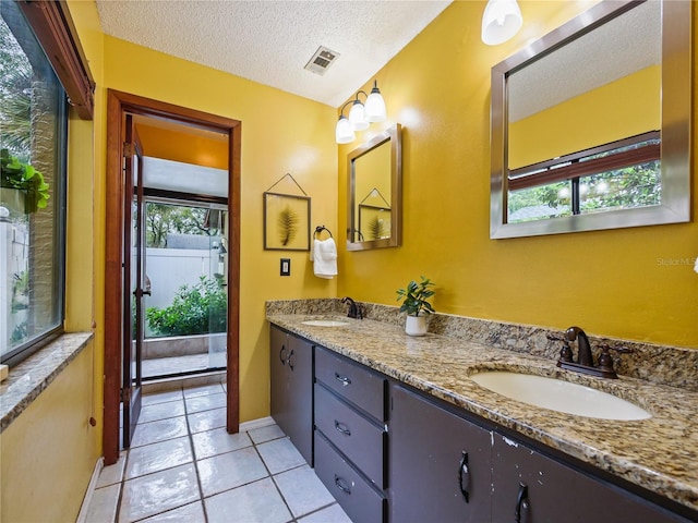 bathroom with tile patterned flooring, visible vents, a sink, and a textured ceiling