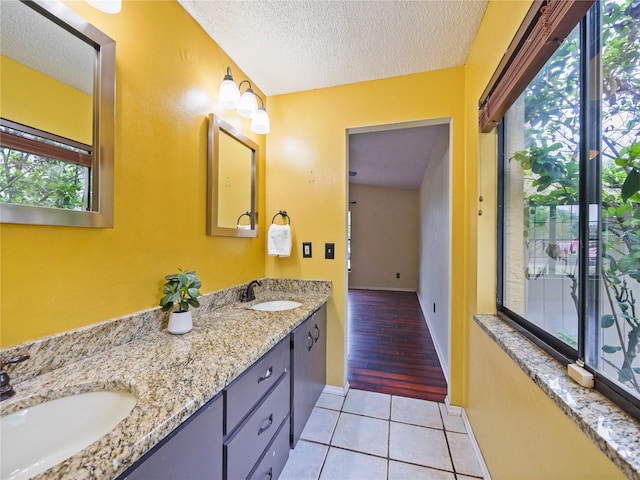 full bathroom featuring double vanity, tile patterned flooring, a textured ceiling, and a sink