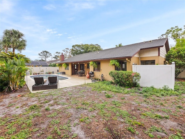 rear view of property featuring a fenced in pool, a patio area, fence, and stucco siding