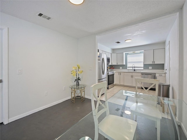 kitchen featuring baseboards, visible vents, stainless steel appliances, light countertops, and a sink