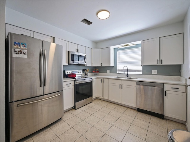 kitchen featuring light tile patterned floors, stainless steel appliances, light countertops, white cabinetry, and a sink