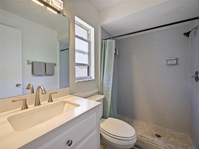 bathroom featuring vanity, a tile shower, and toilet