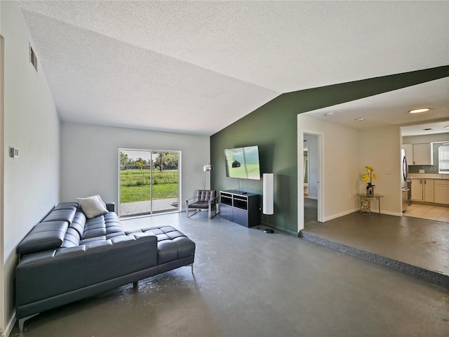 living room featuring concrete flooring, a textured ceiling, lofted ceiling, visible vents, and baseboards