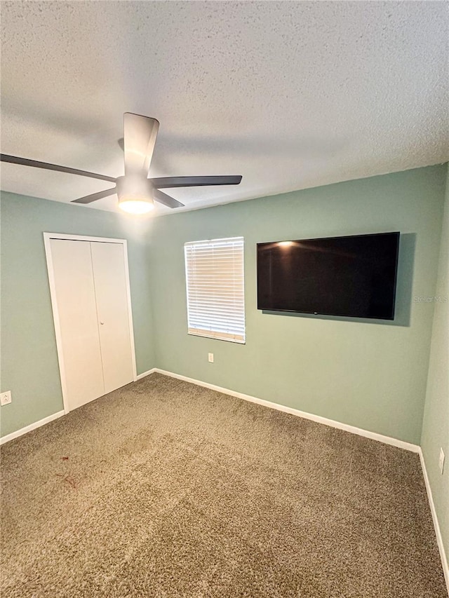 unfurnished bedroom featuring carpet, baseboards, ceiling fan, and a textured ceiling