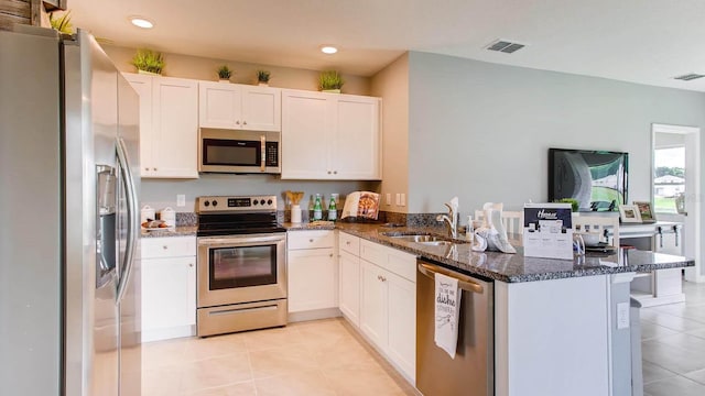 kitchen featuring a peninsula, white cabinetry, stainless steel appliances, and a sink