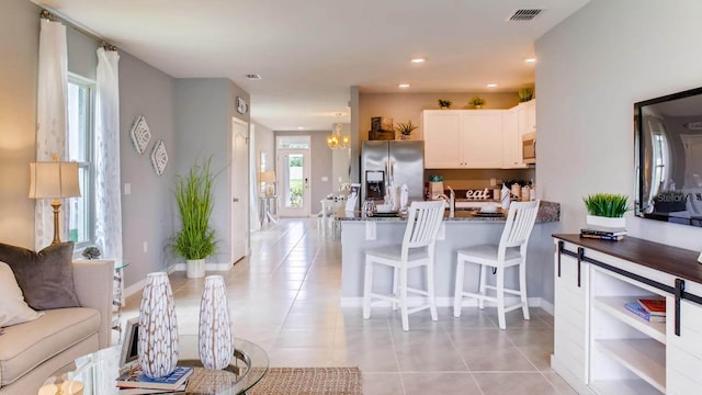 kitchen with light tile patterned floors, visible vents, appliances with stainless steel finishes, a kitchen bar, and white cabinetry