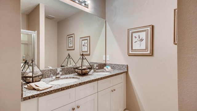 bathroom with double vanity, visible vents, and a sink