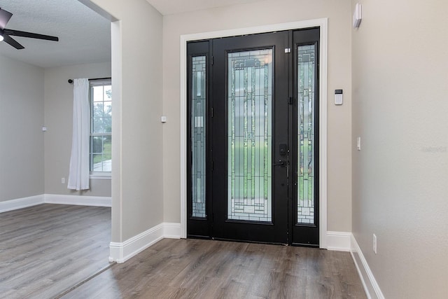 entrance foyer featuring ceiling fan, a textured ceiling, baseboards, and wood finished floors