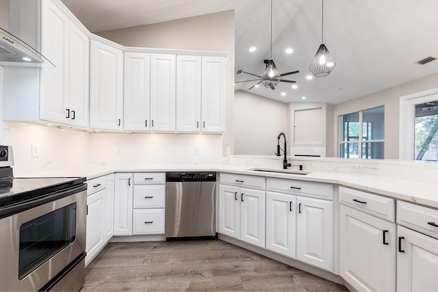 kitchen with lofted ceiling, stainless steel appliances, a sink, visible vents, and wall chimney range hood