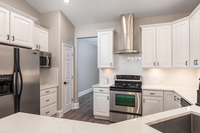 kitchen with stainless steel appliances, wall chimney range hood, and white cabinetry