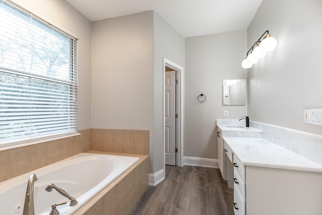 full bathroom with a garden tub, wood finished floors, vanity, and baseboards