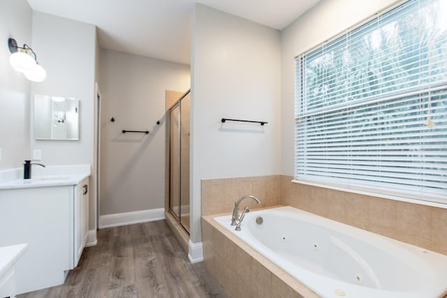 bathroom featuring wood finished floors, a jetted tub, a shower stall, and vanity