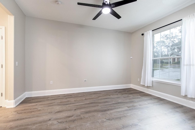 spare room featuring a ceiling fan, baseboards, and wood finished floors