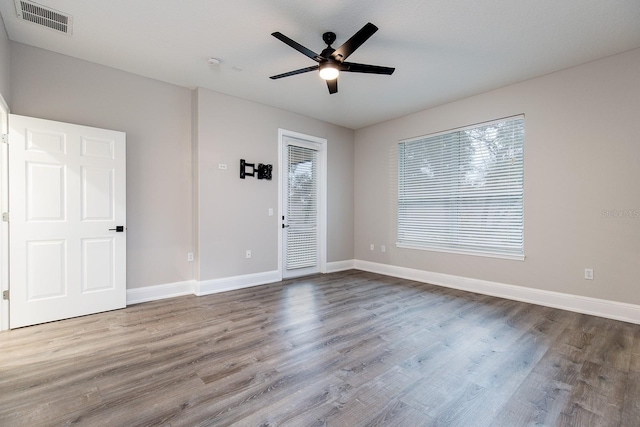 unfurnished room with a ceiling fan, visible vents, baseboards, and wood finished floors