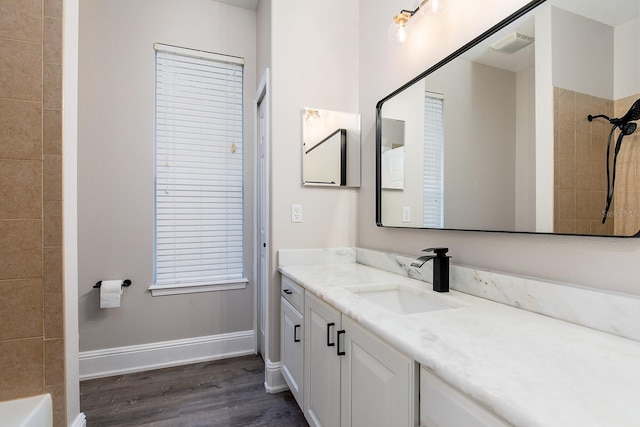 bathroom with wood finished floors, vanity, visible vents, baseboards, and a shower