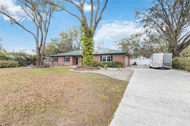 view of front facade with driveway, a front yard, fence, and brick siding