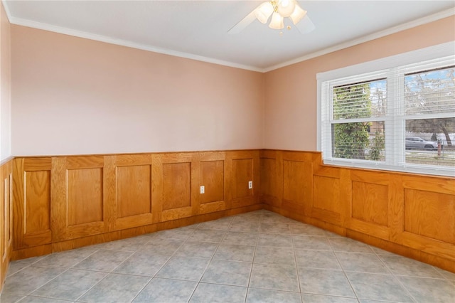 unfurnished room featuring ornamental molding, a ceiling fan, wainscoting, and light tile patterned floors