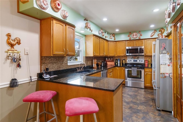 kitchen with brown cabinets, decorative backsplash, appliances with stainless steel finishes, a sink, and a peninsula