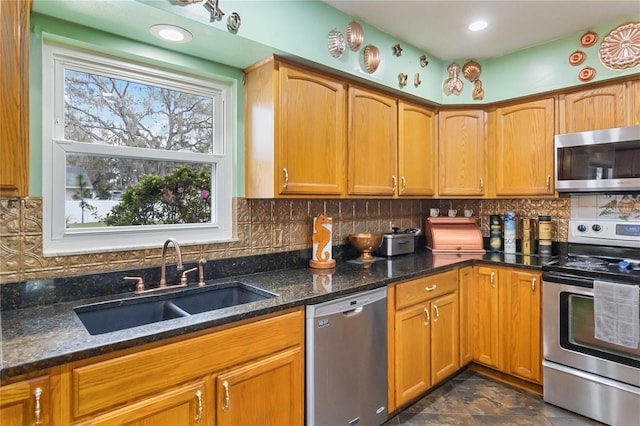 kitchen featuring backsplash, dark stone countertops, stainless steel appliances, and a sink