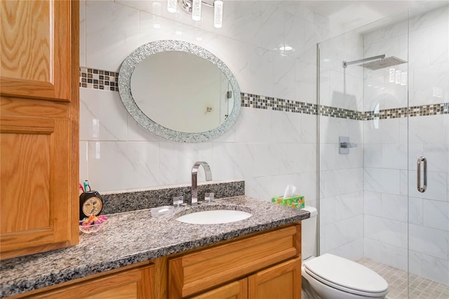 full bath with toilet, a stall shower, tile walls, and vanity