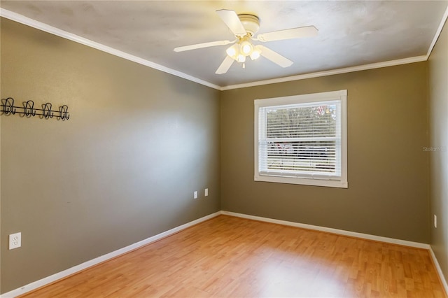 spare room featuring a ceiling fan, light wood-style flooring, baseboards, and crown molding