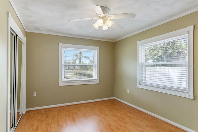 spare room featuring light wood finished floors, a ceiling fan, baseboards, and crown molding