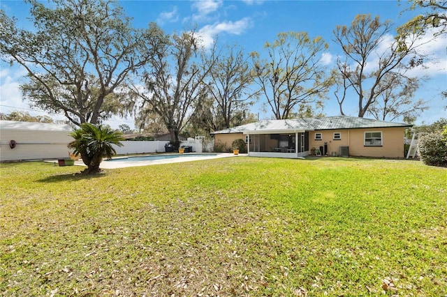 rear view of house featuring a fenced in pool, a lawn, concrete driveway, a sunroom, and fence