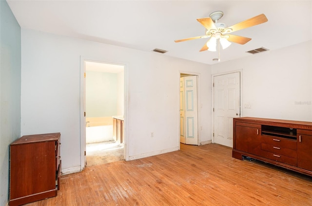 unfurnished bedroom featuring ensuite bathroom, light wood finished floors, visible vents, and baseboards