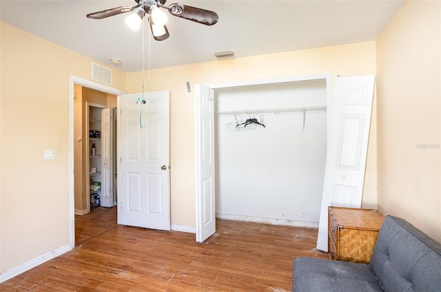 interior space with ceiling fan, wood finished floors, visible vents, and baseboards