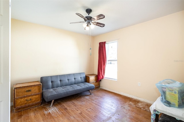 sitting room featuring a ceiling fan, baseboards, and wood finished floors