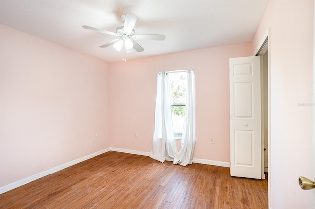 unfurnished room featuring a ceiling fan, light wood-type flooring, and baseboards