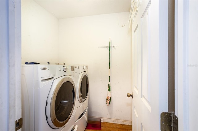 laundry room featuring wood finished floors, laundry area, baseboards, and separate washer and dryer