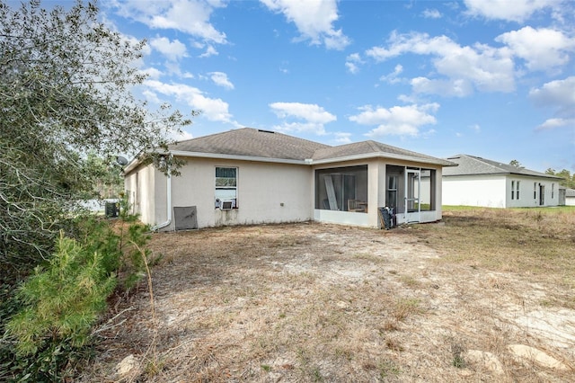 rear view of house with a sunroom and stucco siding