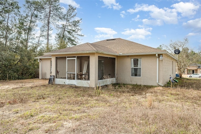 back of house with a sunroom, a shingled roof, and stucco siding