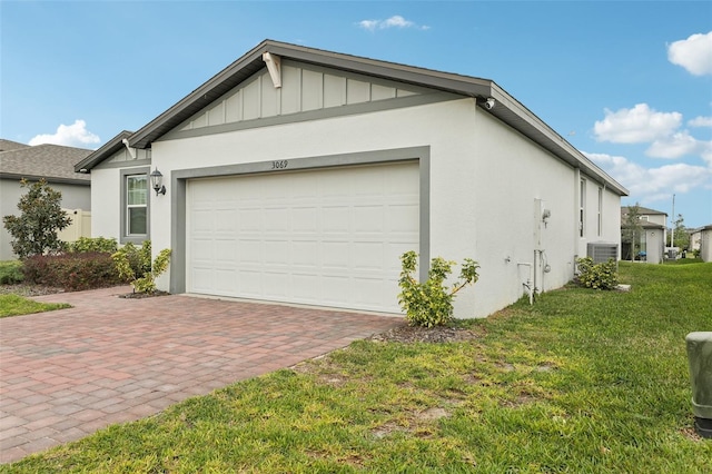 view of side of home featuring a garage, decorative driveway, a lawn, and stucco siding