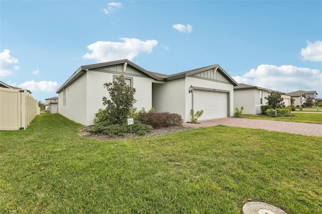 view of front of home with decorative driveway, stucco siding, an attached garage, fence, and a front lawn