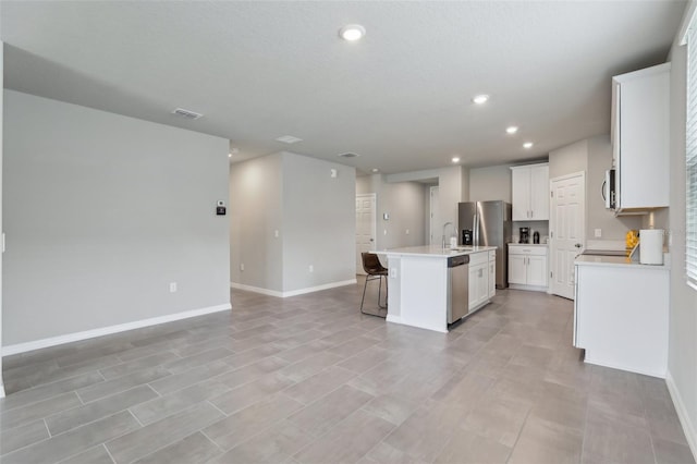 kitchen featuring a center island with sink, light countertops, open floor plan, white cabinets, and a sink