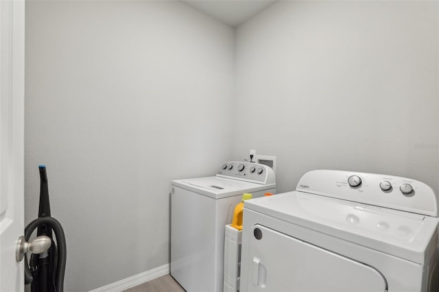 clothes washing area with laundry area, separate washer and dryer, light wood-type flooring, and baseboards